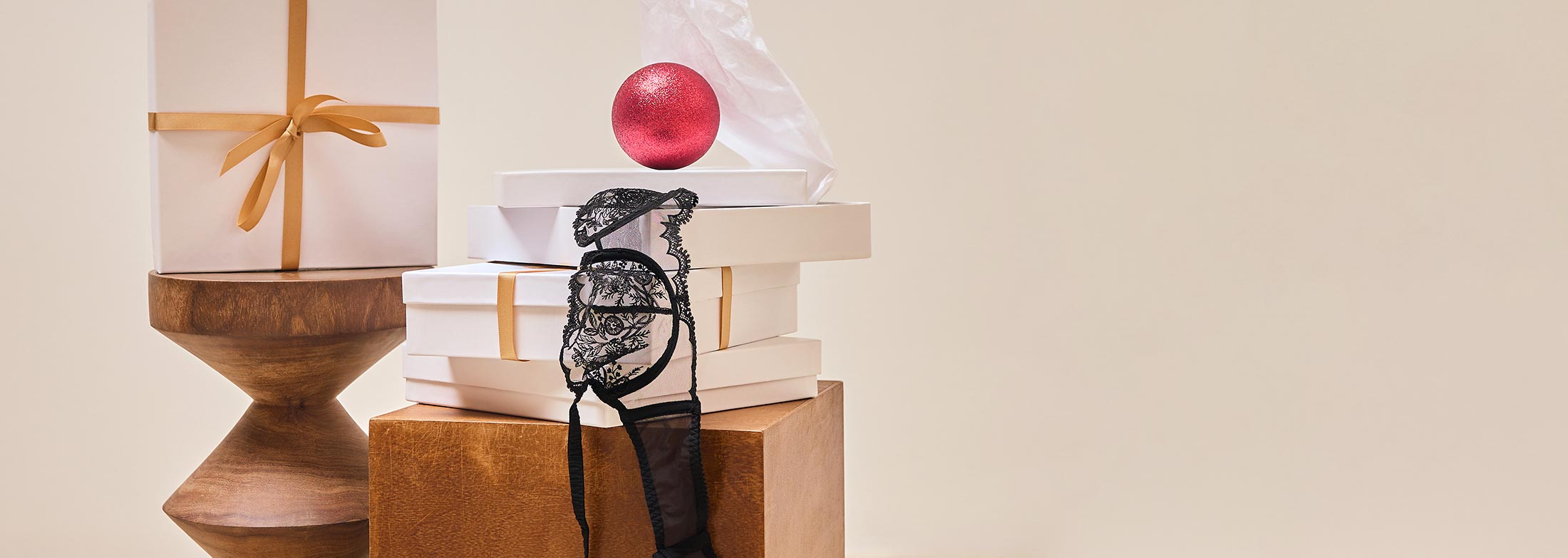 Simone Perele gift boxes on wood pedestals with a black lace demi bra and red ornament